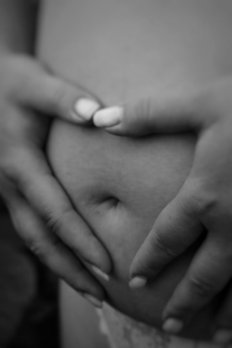 grayscale photography of hands on belly
